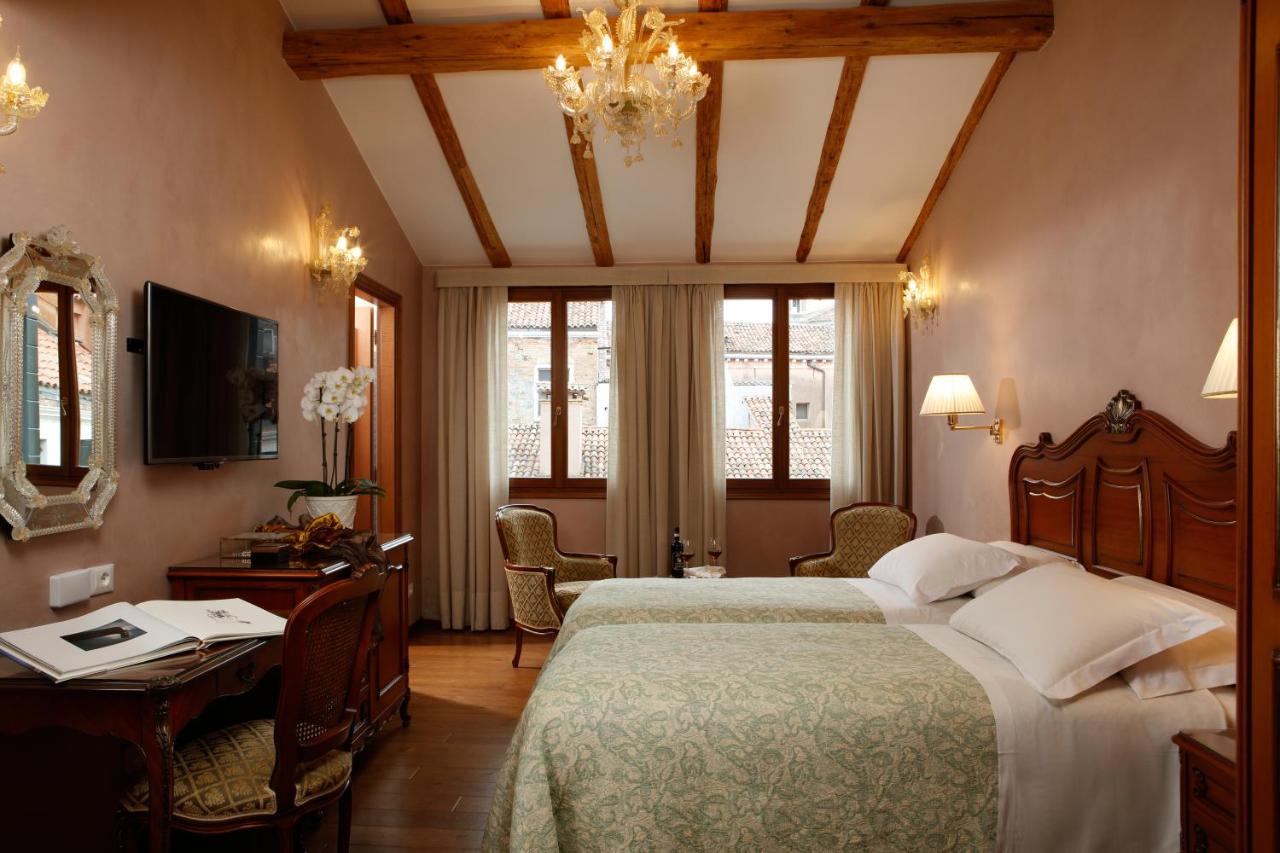 een slaapkamer met een bed, een bureau en een televisie bij Hotel Bisanzio in Venetië