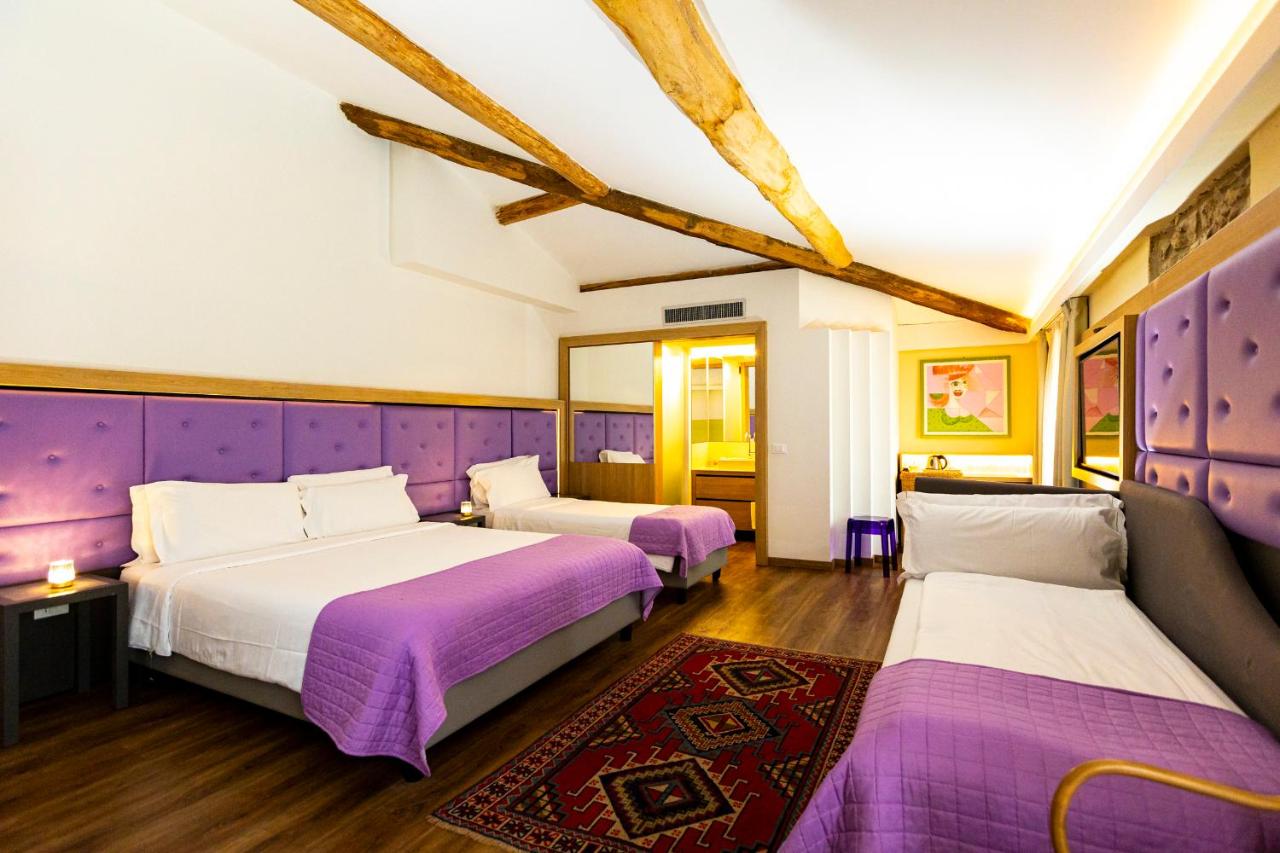 twee bedden in een kamer met paarse en witte accenten bij Hotel Corona in Spiazzi Di Caprino