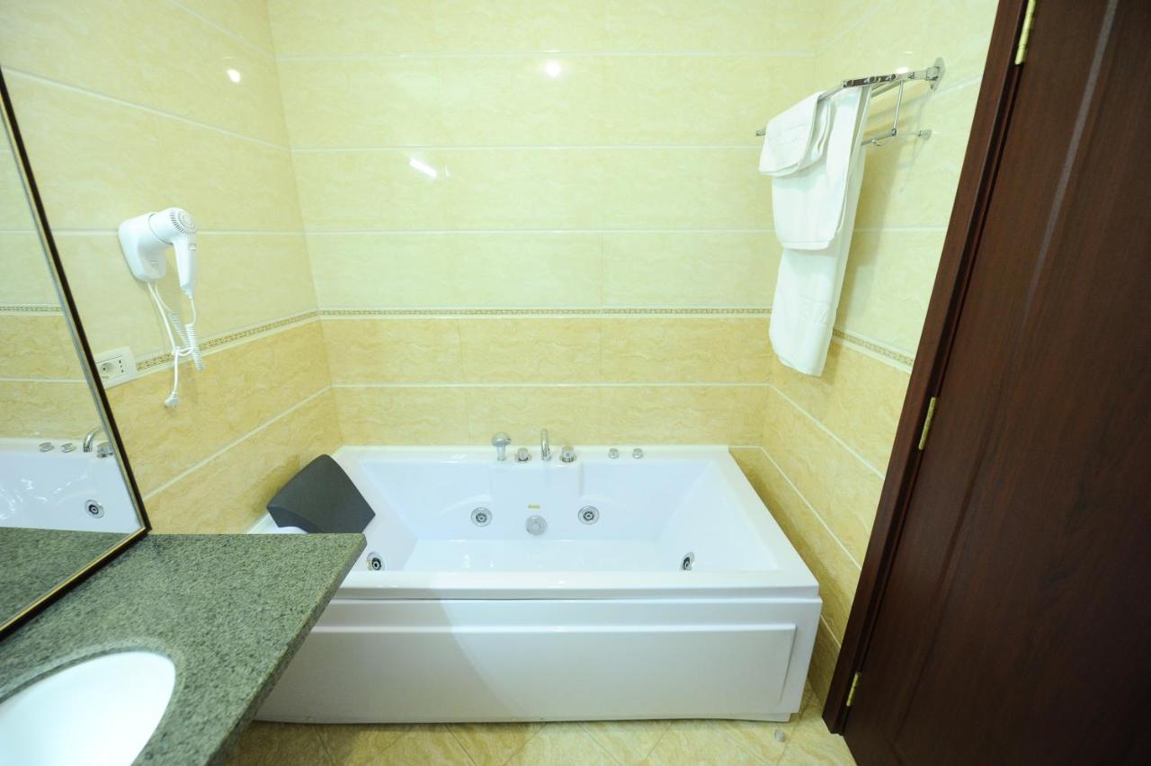 een wit bad in een badkamer met een wastafel bij Hotel Mondial - Baia in Baia