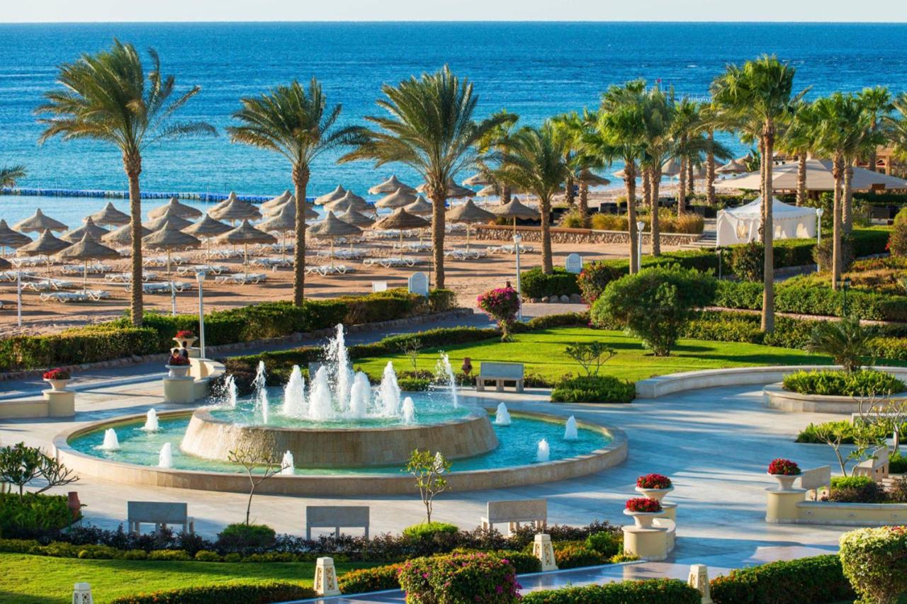 een fontein voor een strand met palmbomen en de oceaan bij Baron Resort Sharm El Sheikh in Sharm El Sheikh
