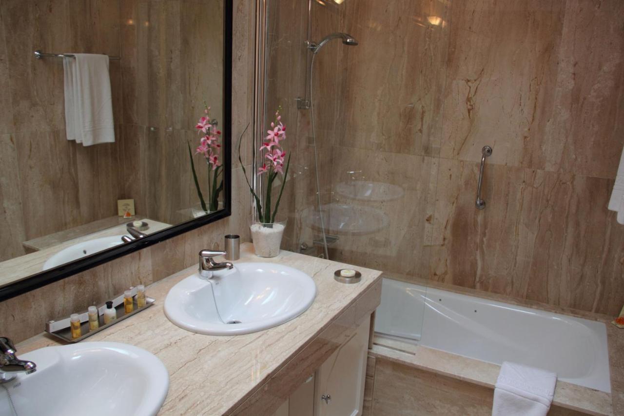 een badkamer met twee wastafels, een spiegel en een badkuip bij Villa VIK - Hotel Boutique in Arrecife