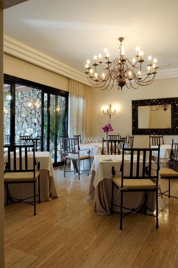 een eetkamer met tafels en stoelen en een kroonluchter bij Villa VIK - Hotel Boutique in Arrecife