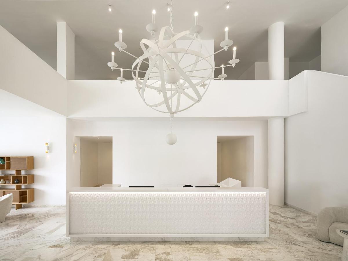 een witte woonkamer met een kroonluchter bij Grecotel Casa Adele in Platanes