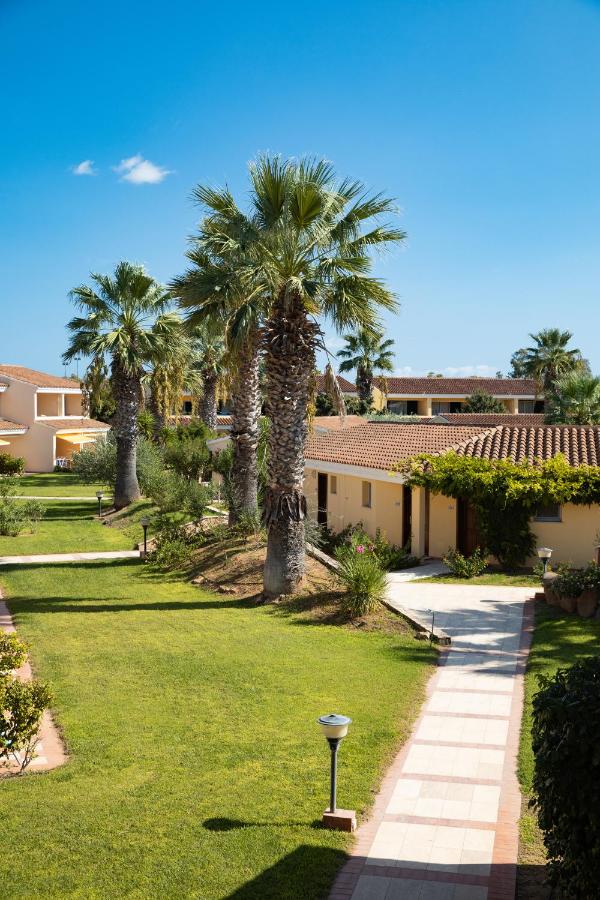een gazon met palmbomen voor een huis bij Sentido Tirreno Resort in Cala Liberotto