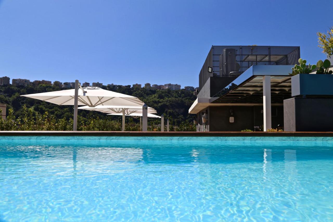 een zwembad met een parasol en een gebouw bij LHP Napoli Palace & SPA in Napels