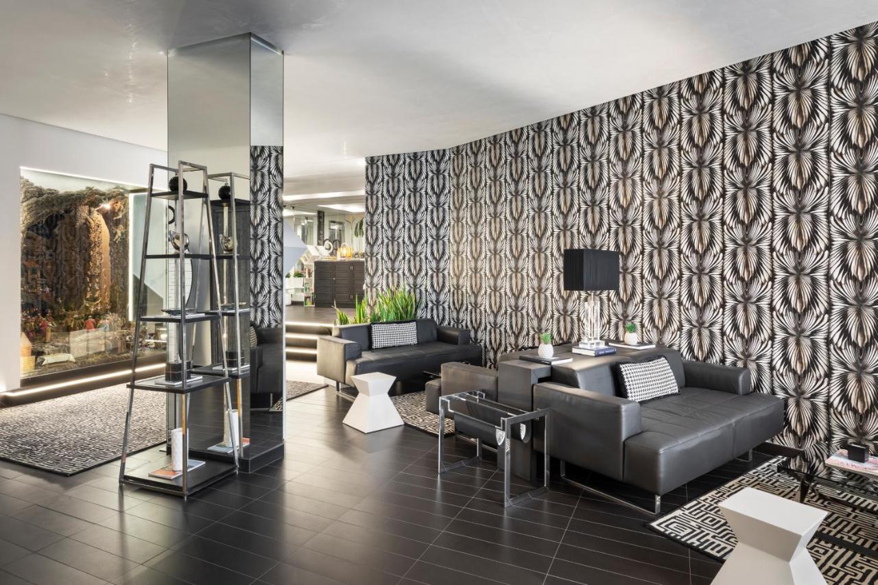 een woonkamer met een bank en stoelen en een muur bij LHP Napoli Palace & SPA in Napels