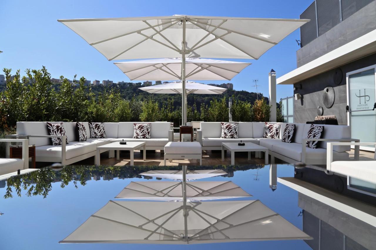 een terras met witte stoelen en parasols en een zwembad bij LHP Napoli Palace & SPA in Napels