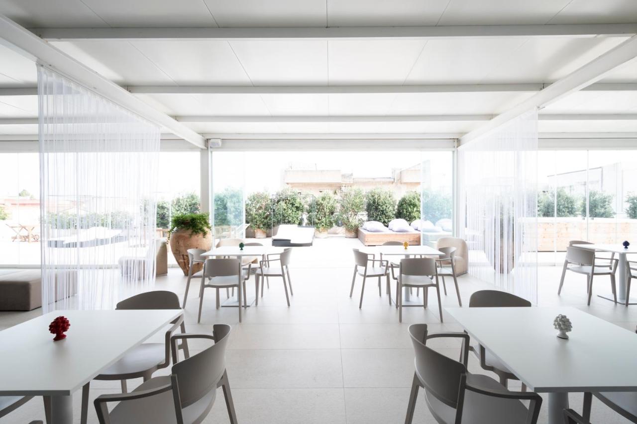 een restaurant met witte tafels en stoelen en grote ramen bij Alkamuri Posh Hotel e Spa in Alcamo