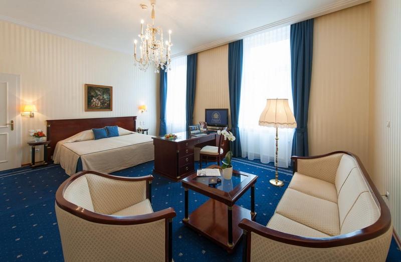 een hotelkamer met een bed, stoelen en een tafel bij Hotel Ambassador in Wenen