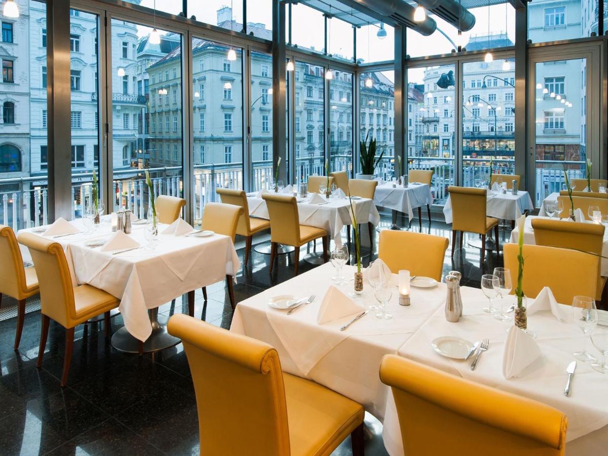 een restaurant met tafels, stoelen en ramen bij Hotel Ambassador in Wenen +49 foto's