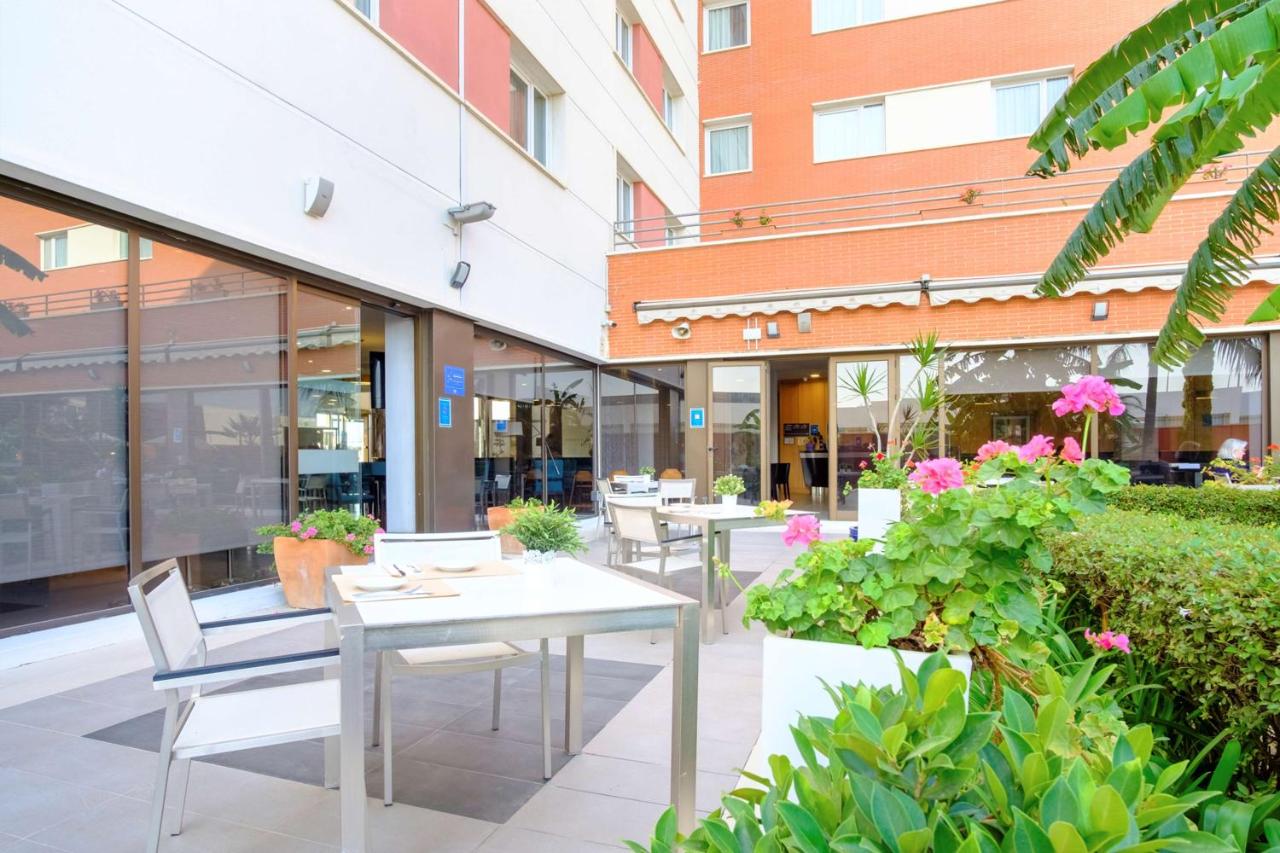 een terras met tafels en stoelen in een gebouw bij Hilton Garden Inn Málaga in Málaga