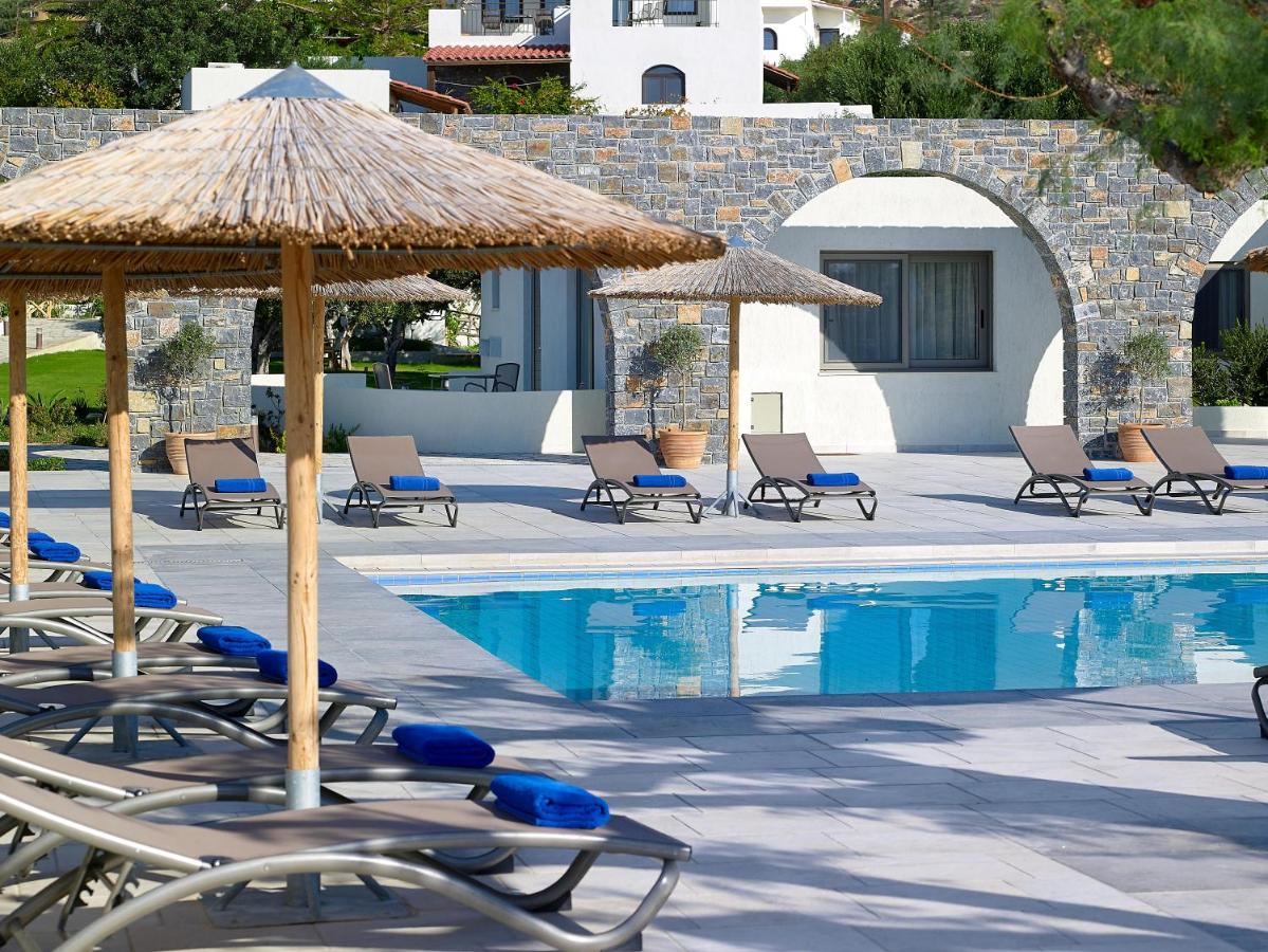 een groep stoelen en parasols naast een zwembad bij Coriva Beach Hotel & Bungalows in Koutsounari