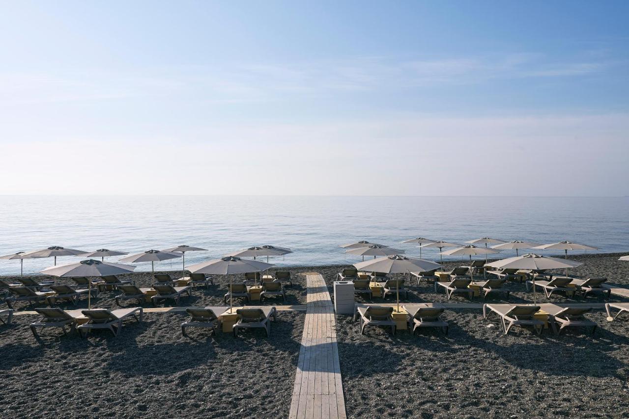 een strand met tafels, stoelen en parasols bij Coriva Beach Hotel & Bungalows in Koutsounari