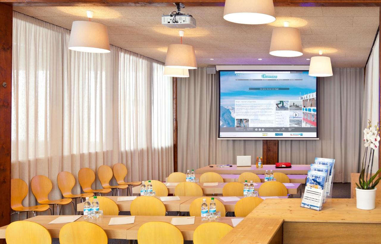 een vergaderruimte met tafels en stoelen en een projectiescherm bij Glacier Hotel Grawand in Maso Corto