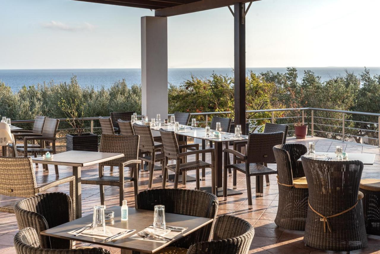 een restaurant met tafels en stoelen met de oceaan op de achtergrond bij Porto Belissario in Ferma