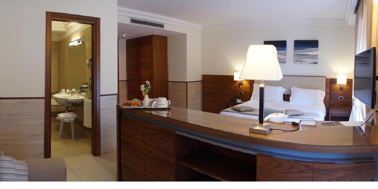 een slaapkamer met een bed en een bureau met een lamp bij Suites & Residence Hotel in Pozzuoli