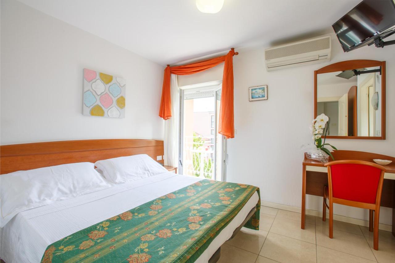 een slaapkamer met een bed, een bureau en een spiegel bij Hotel Ada in Rimini