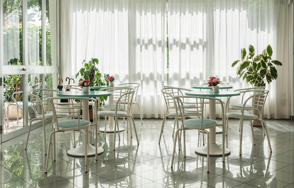 een eetkamer met tafels en stoelen en ramen bij Hotel Ada in Rimini +18 foto's