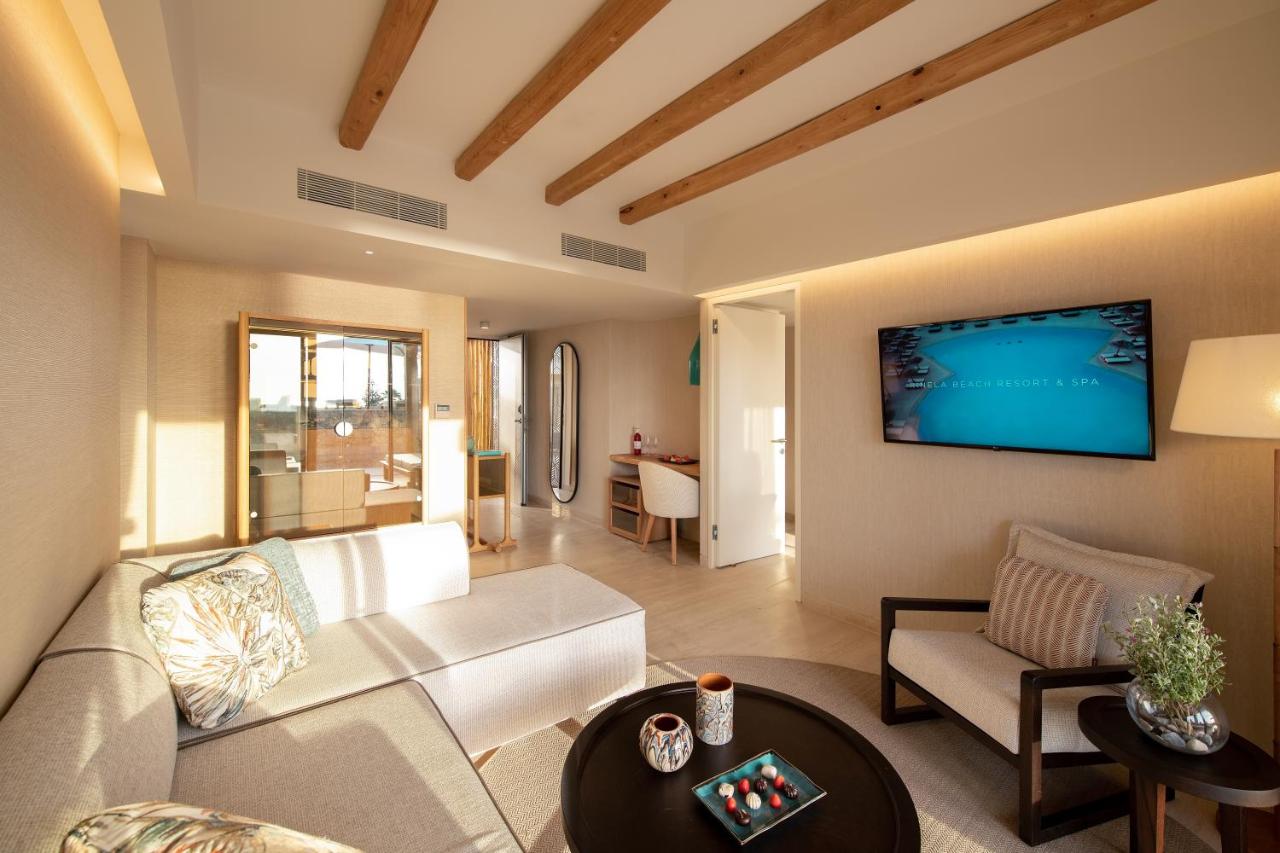 een woonkamer met een bank en een tv aan de muur bij Mitsis Selection Rinela in Kokkíni Khánion