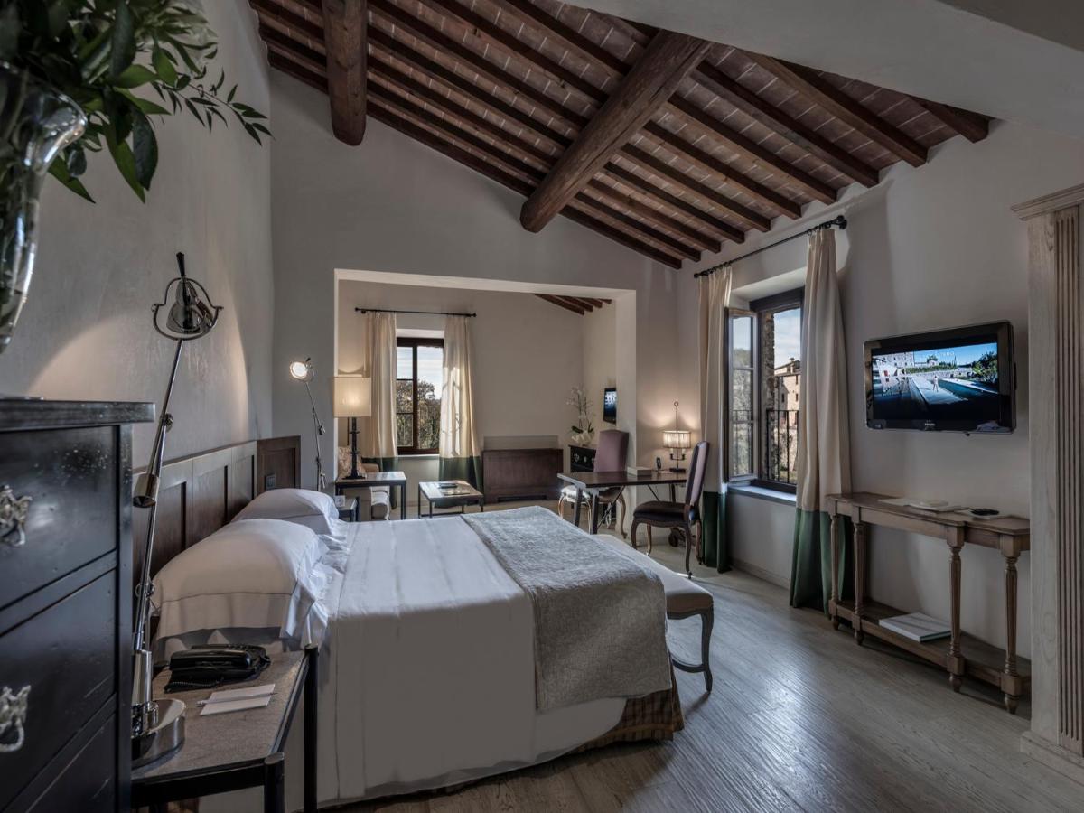 een slaapkamer met een bed en een televisie erin bij Castel Monastero - The Leading Hotels of the World in Castelnuovo B