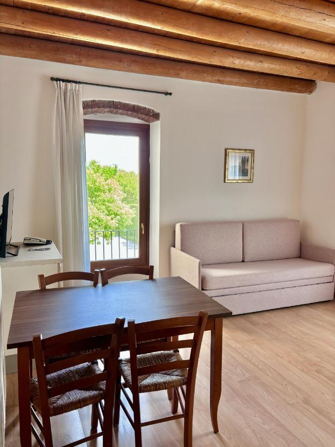 een woonkamer met een tafel, stoelen en een bank bij Hotel Bella Italia in Peschiera del Garda