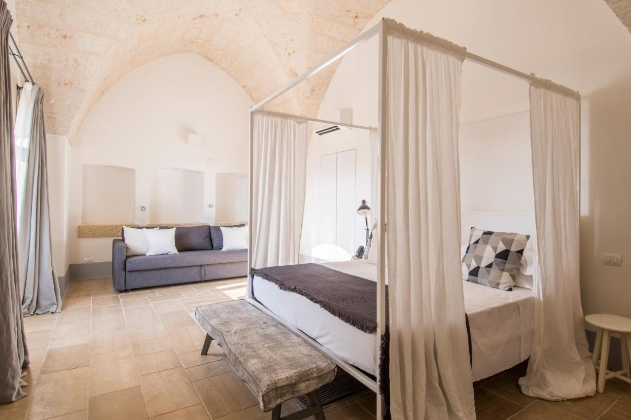 een slaapkamer met een bed en een bank bij Masseria San Giovanni - Epoca Collection in Fasano