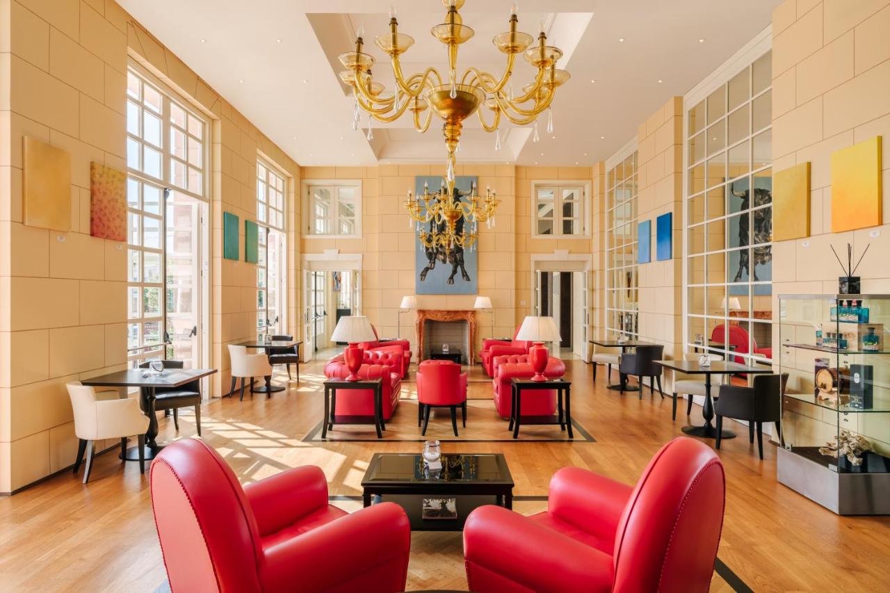 een woonkamer met rode stoelen en tafels en een kroonluchter bij Grand Hotel Bristol Spa Resort, by R Collection Hotels 