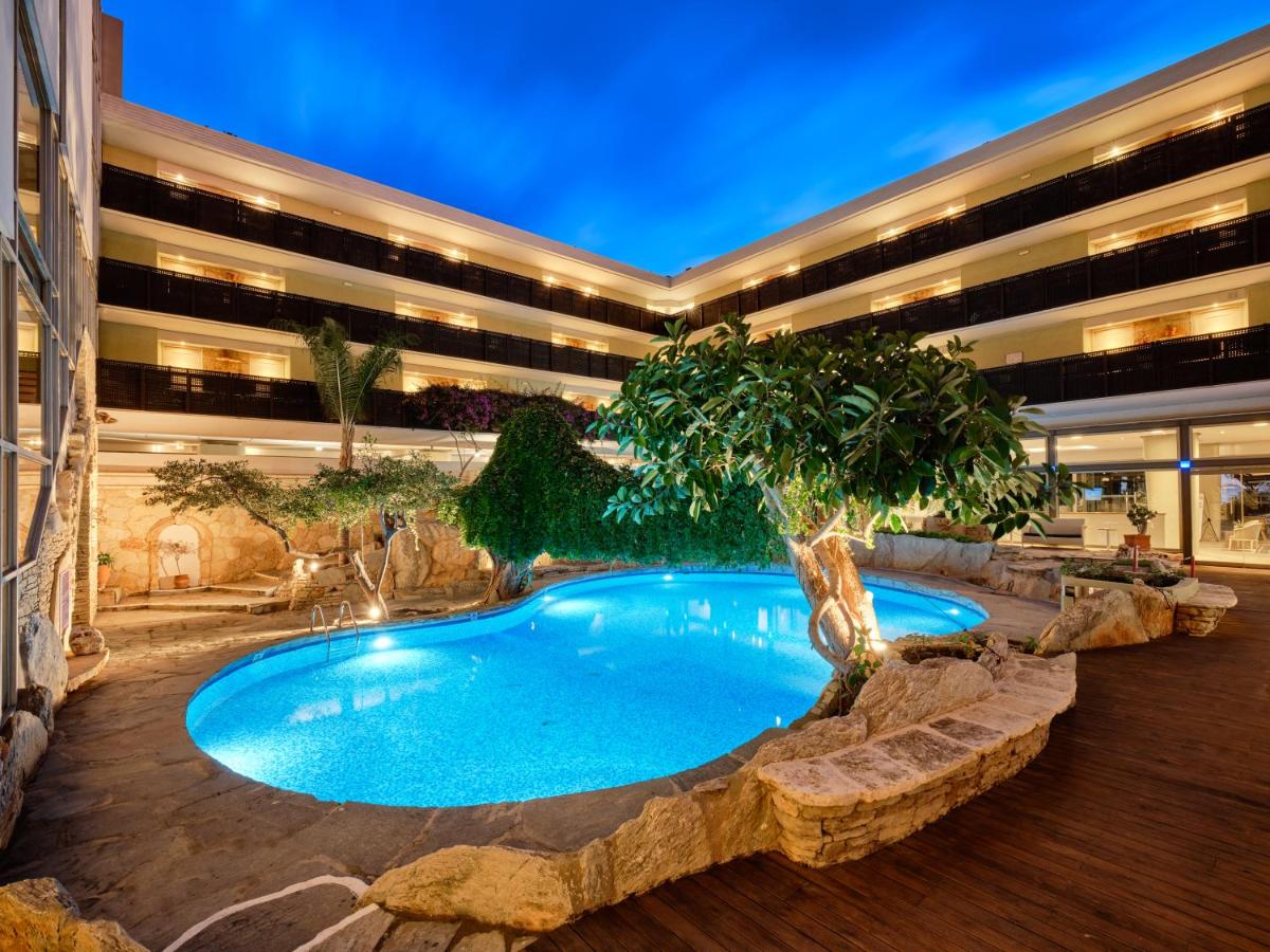 een gebouw met een zwembad met een boom erin bij Sitia Beach City Resort & Spa in Sitia