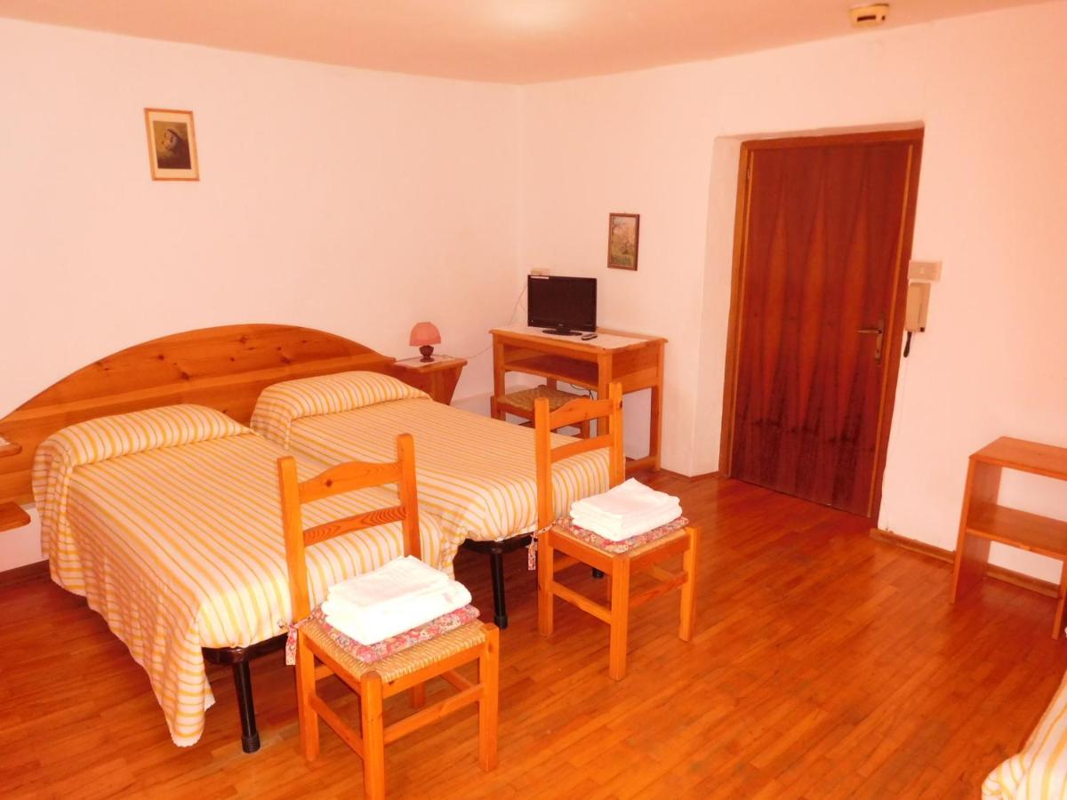 een slaapkamer met een bed, twee stoelen en een bureau bij Antico Albergo Sant'Antonio in Fonzaso
