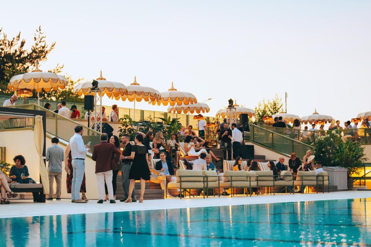 een groep mensen die rond een zwembad staan bij Living Place Hotel in Villanova