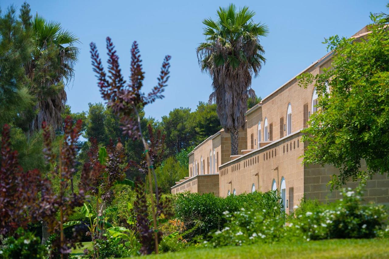 een groot bakstenen gebouw met palmbomen op de achtergrond bij Vivosa Apulia Resort in Ugento