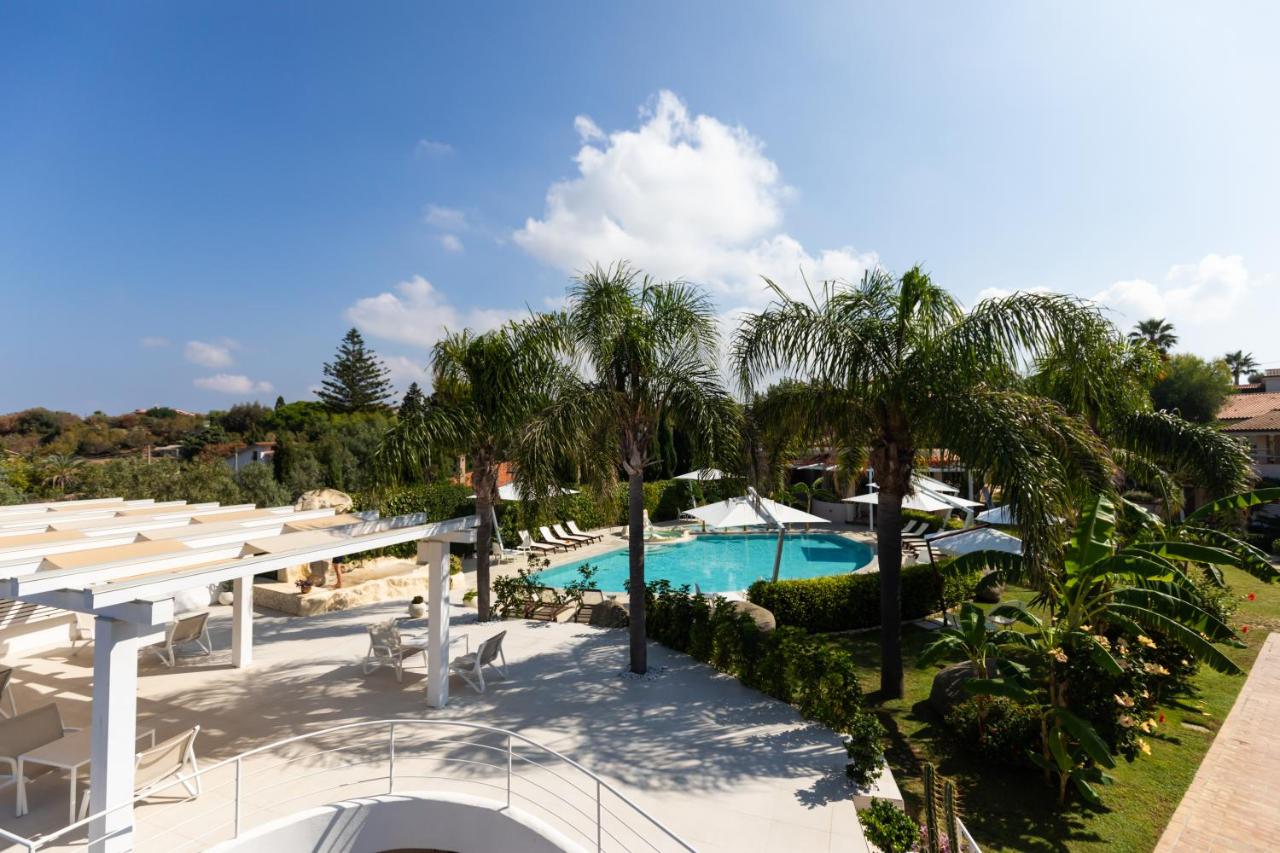 een uitzicht op het zwembad van een resort met palmbomen bij L' Arcobaleno Resort in Capo Vaticano