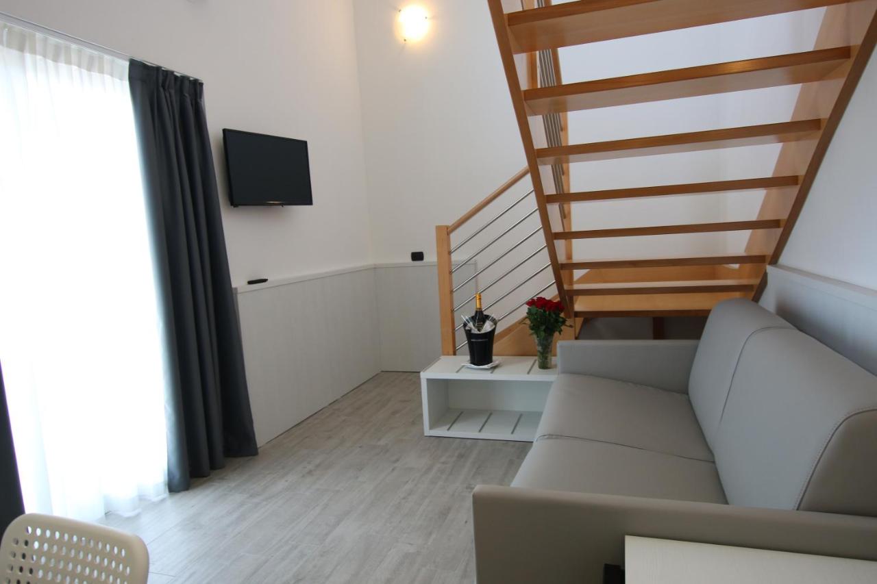 een woonkamer met een bank en een trap bij Eraclea Palace Hotel 4 stelle S in Eraclea Mare