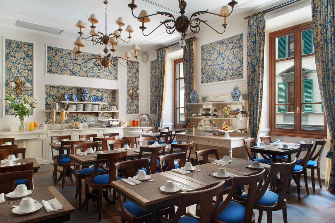 een restaurant met houten tafels en stoelen in een kamer bij FH55 Hotel Calzaiuoli in Florence