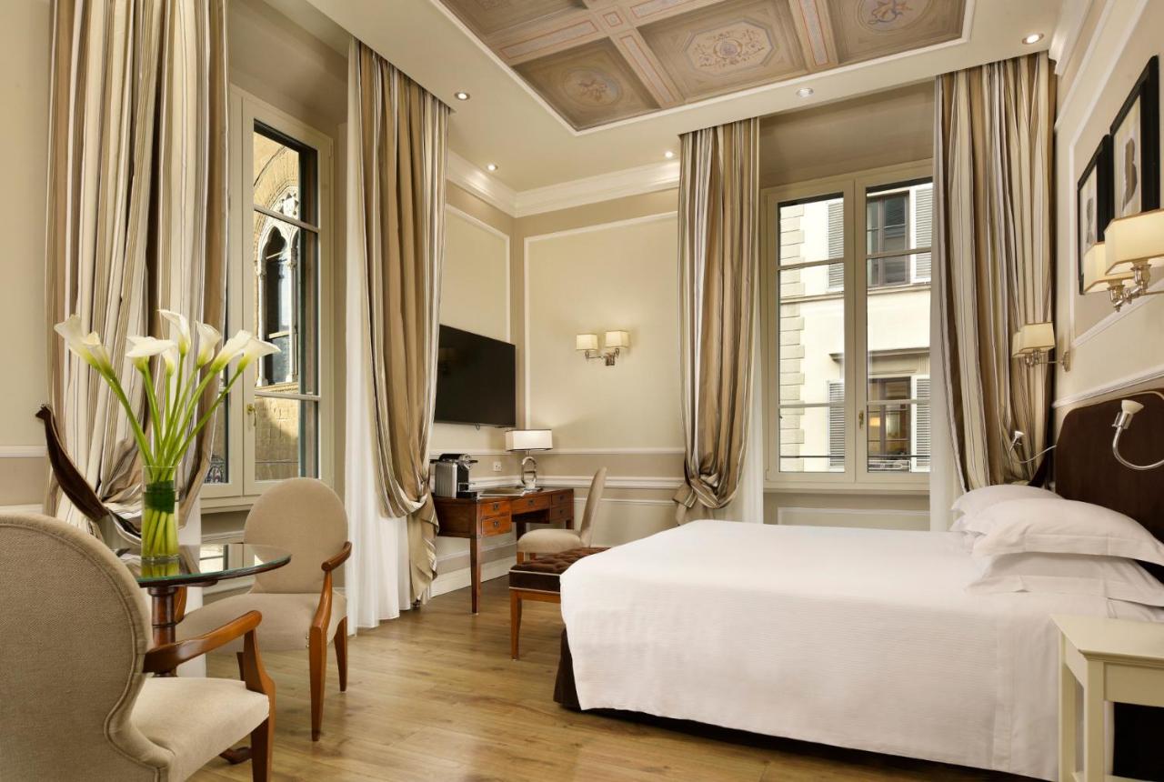 een slaapkamer met een wit bed, een bureau en een tafel bij FH55 Hotel Calzaiuoli in Florence
