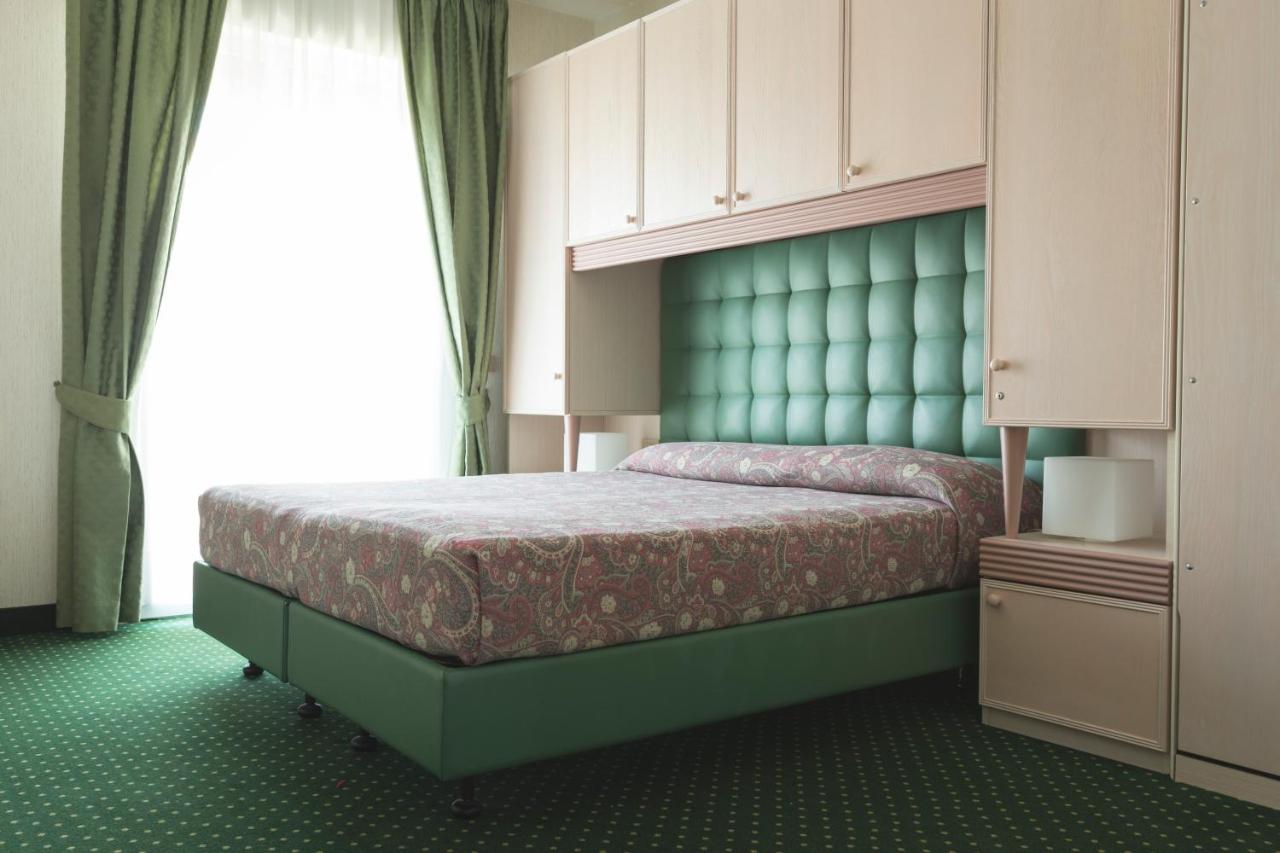 een slaapkamer met een bed met een groen hoofdeinde bij Hotel Cambridge in Lido di Jesolo +51 foto's