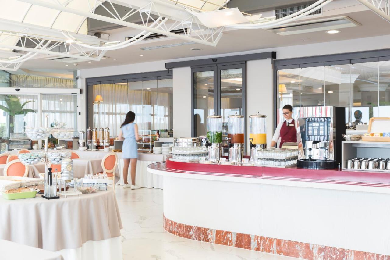 een restaurant met twee mensen die aan een toonbank staan bij Hotel Cambridge in Lido di Jesolo