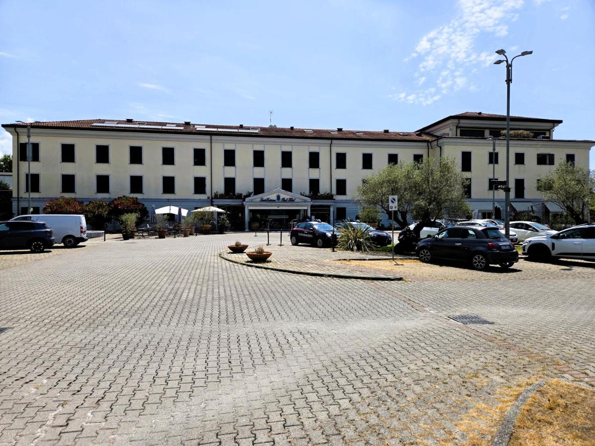 een groot wit gebouw met auto's geparkeerd op een parkeerplaats bij Santa Caterina Park Hotel in Sarzana