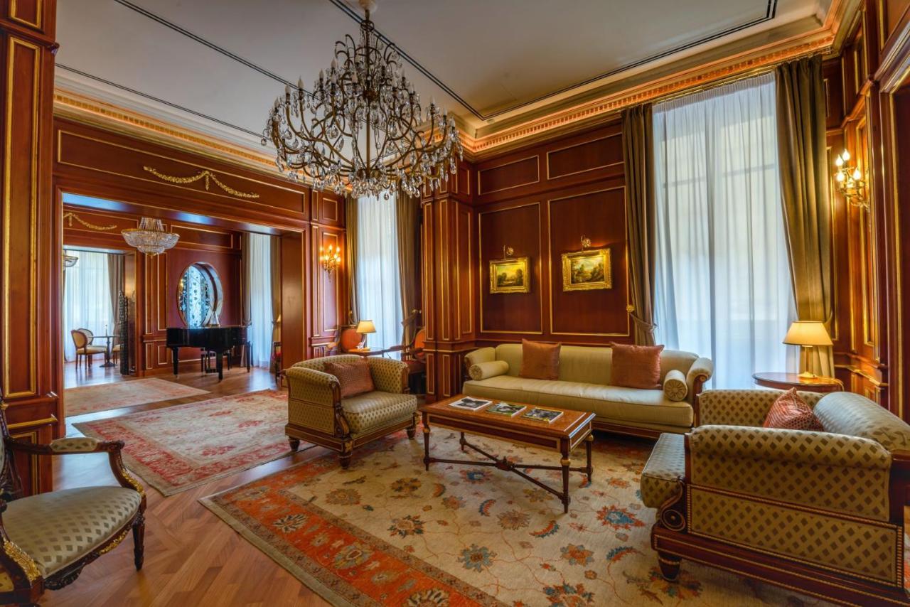 een woonkamer met een bank, stoelen en een kroonluchter bij Grand Hotel Wagner in Palermo