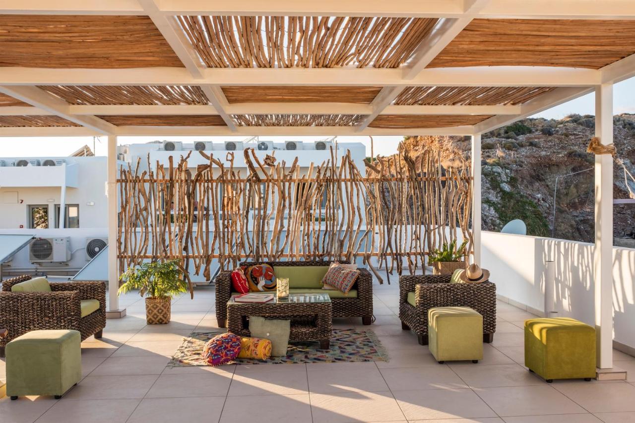 een terras met stoelen en tafels en een kroonluchter bij Aris Boutique Hotel in Palaiochóra