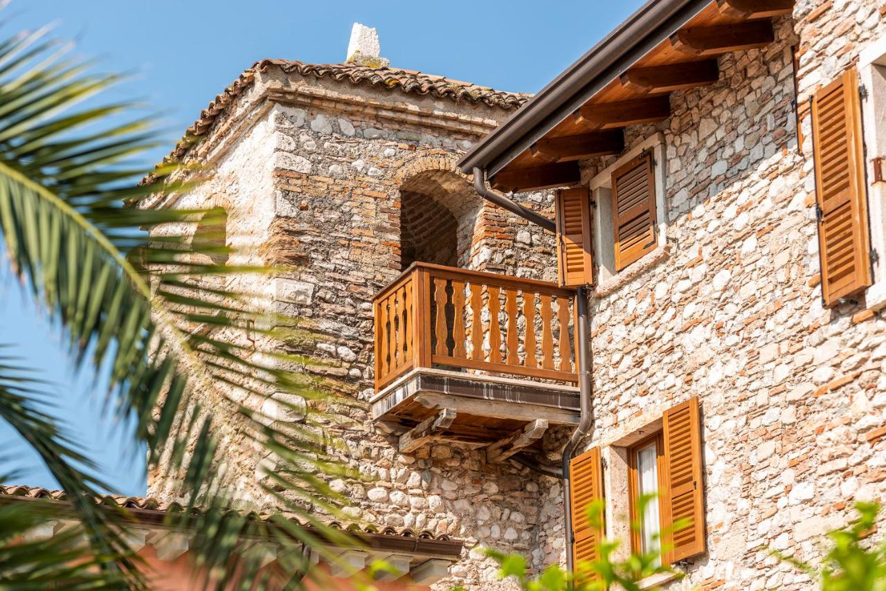 een stenen gebouw met een houten balkon bij Hotel Antico Monastero in Toscolano Maderno