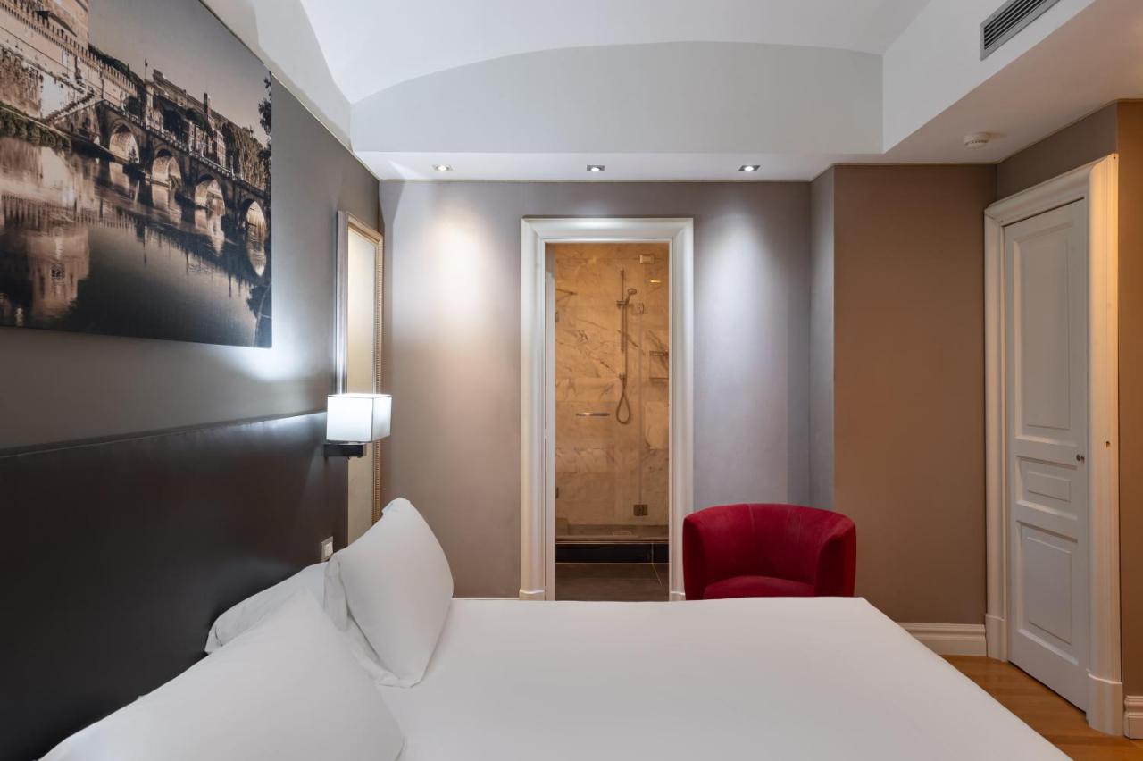 een slaapkamer met een wit bed en een rode stoel bij Hotel Principe Torlonia in Rome