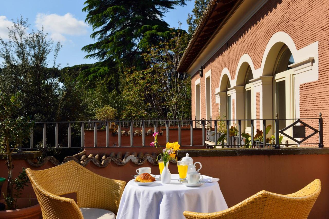 een tafel met een wit tafelkleed en stoelen op een balkon bij Hotel Principe Torlonia in Rome