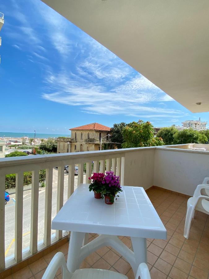 een witte tafel op een balkon met bloemen erop bij Residence T2 in Rimini
