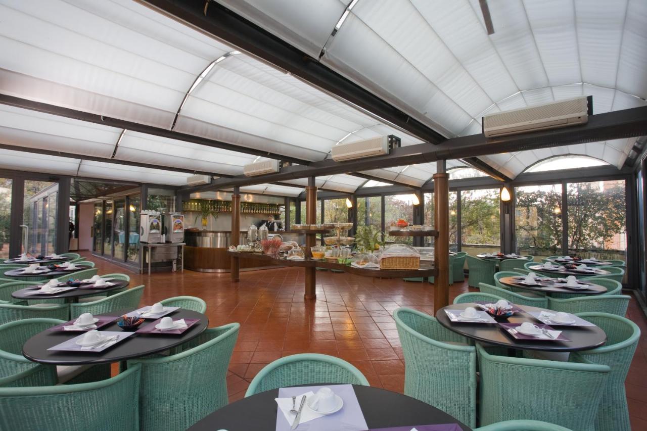 een eetkamer met tafels en stoelen en een keuken bij Ateneo Garden Palace in Rome