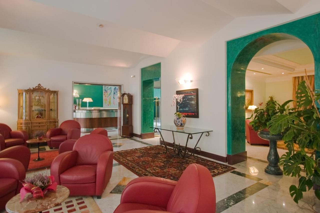 een woonkamer met rode stoelen en een tafel bij Ateneo Garden Palace in Rome