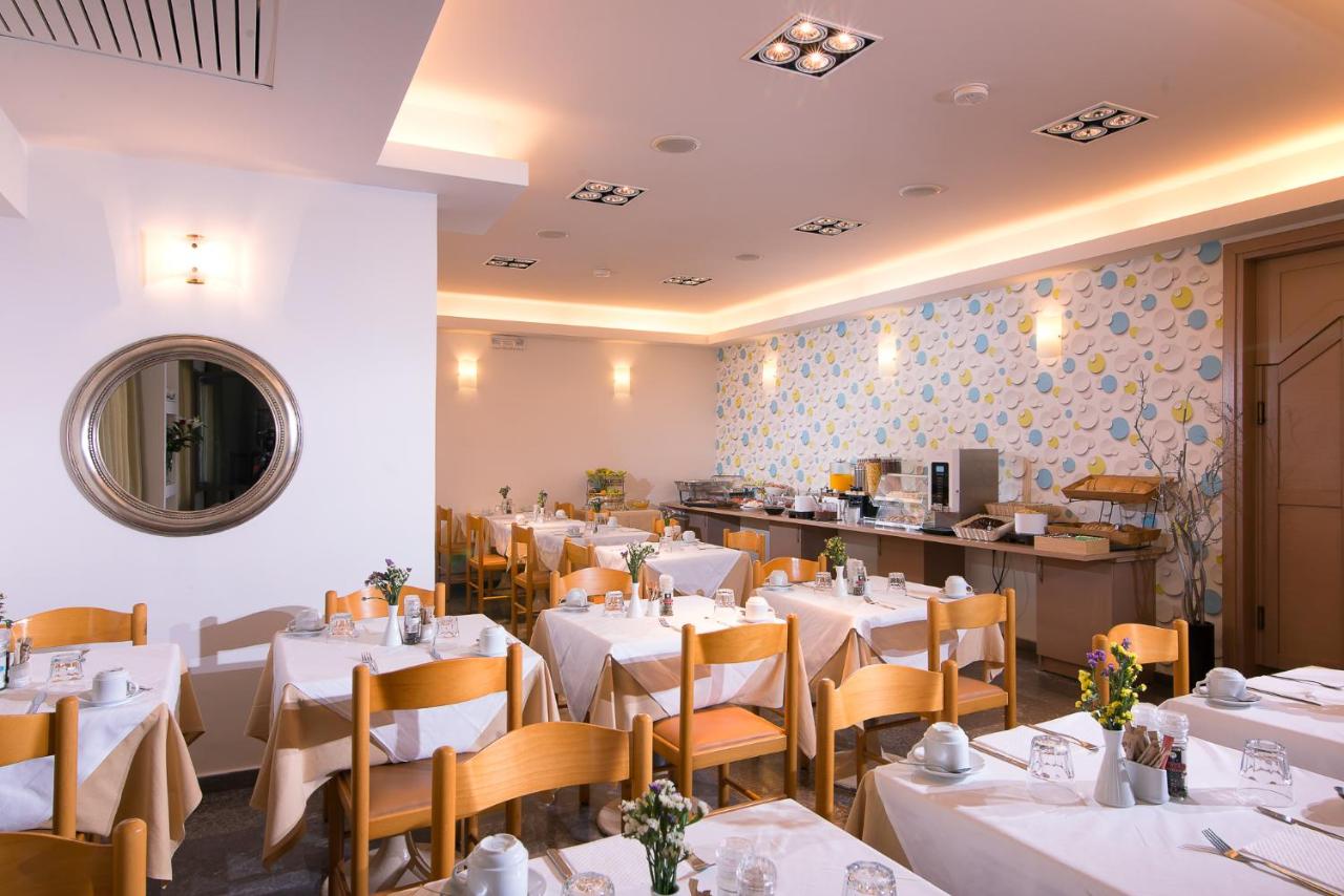 een restaurant met witte tafels en stoelen en een toonbank bij Panormo Beach Hotel in Panormos Rethymno