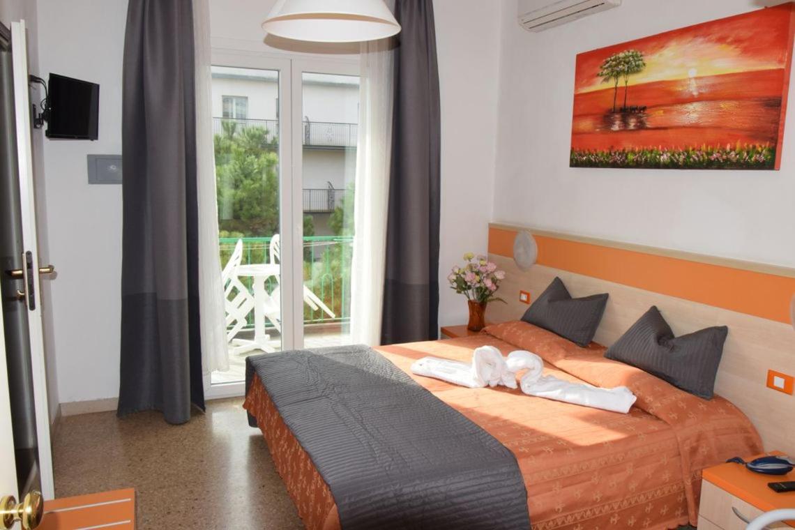 een slaapkamer met een bed waarop twee handdoeken liggen bij Hotel Verdi in Lido di Jesolo +124 foto's