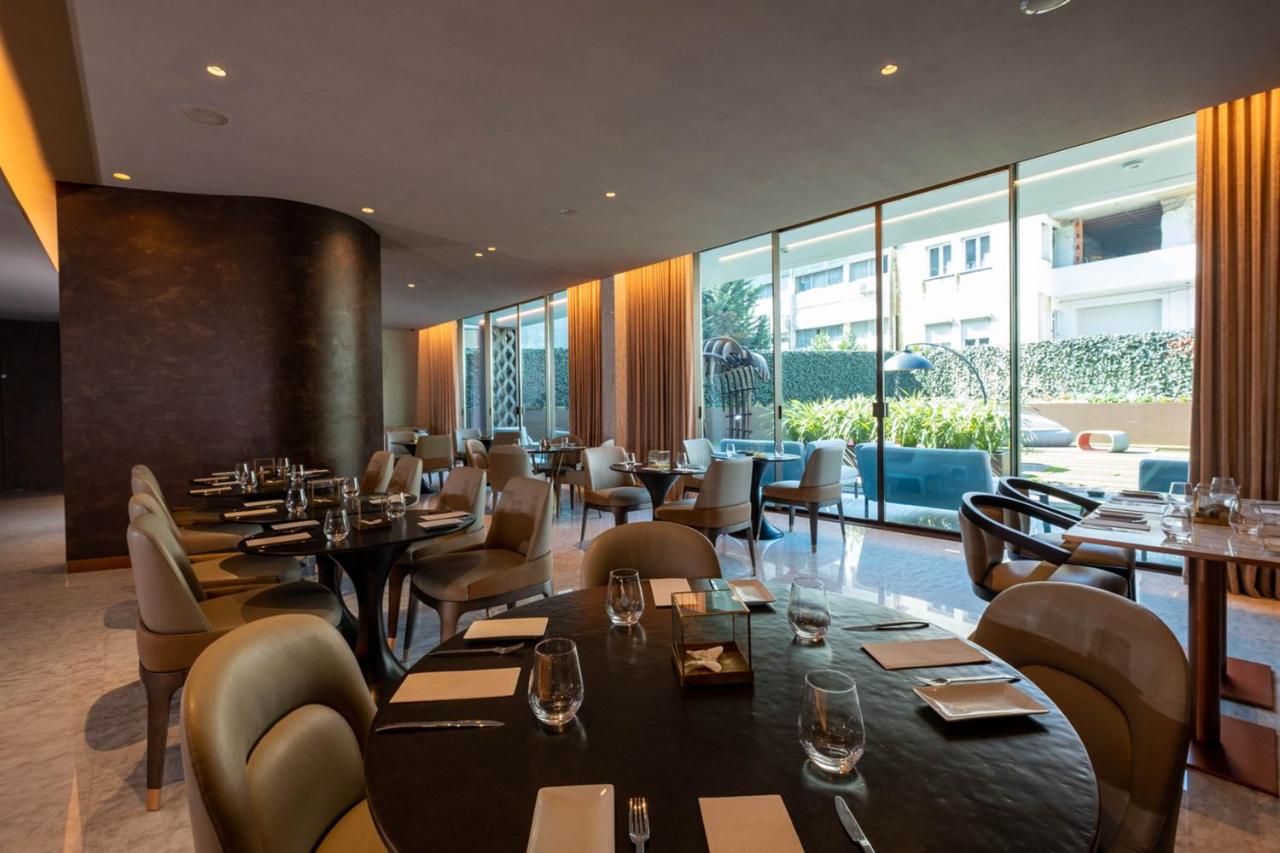 een restaurant met tafels en stoelen en grote ramen bij BessaHotel Baixa in Porto