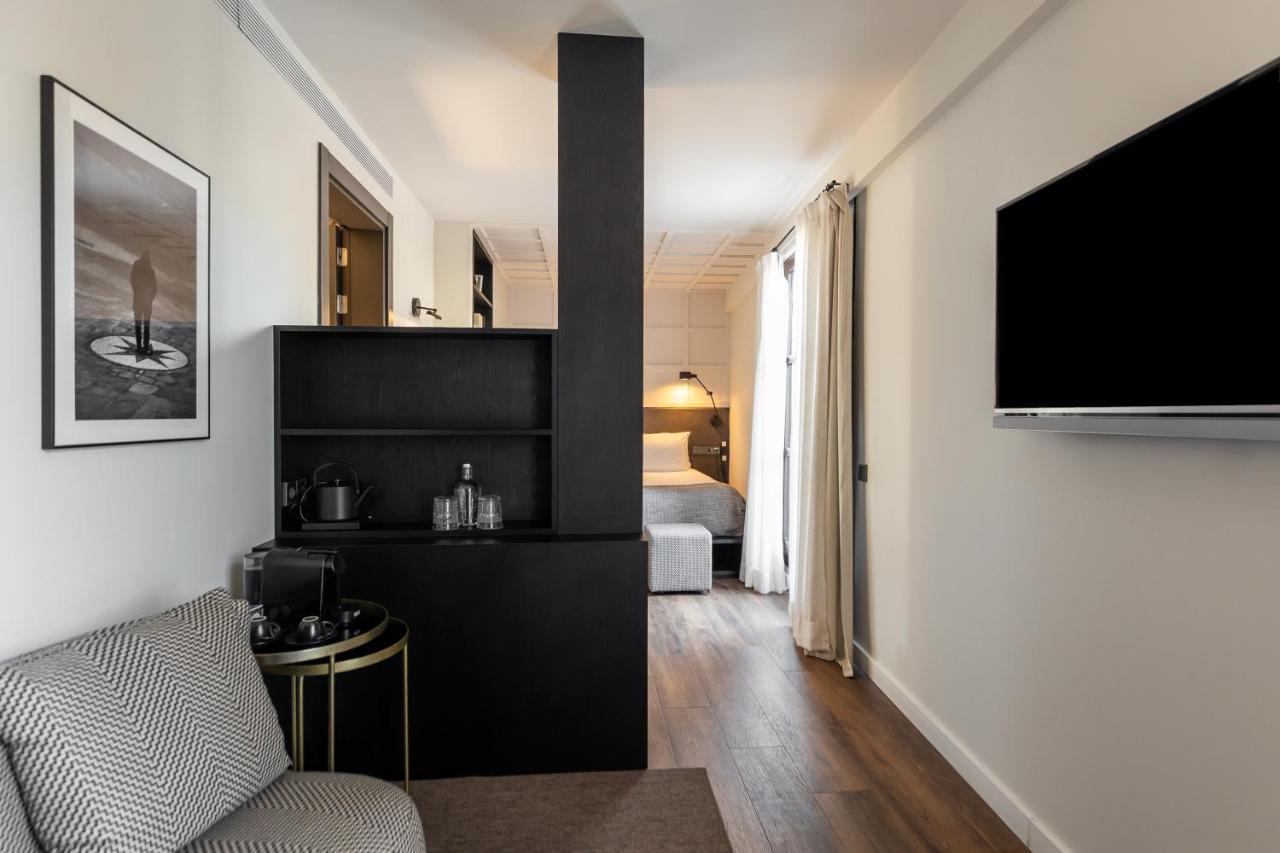 een woonkamer met een bank en een tv aan de muur bij Yurbban Ramblas Boutique Hotel in Barcelona